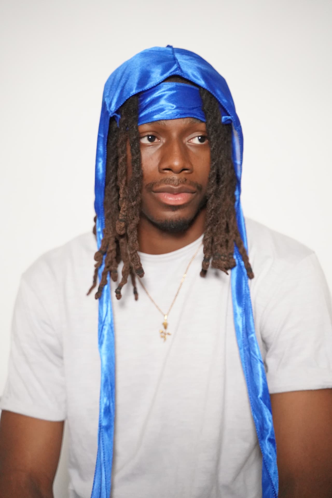 Model with locs wearing the blue Elite Wrap with the flap draped over the shoulders and long ties