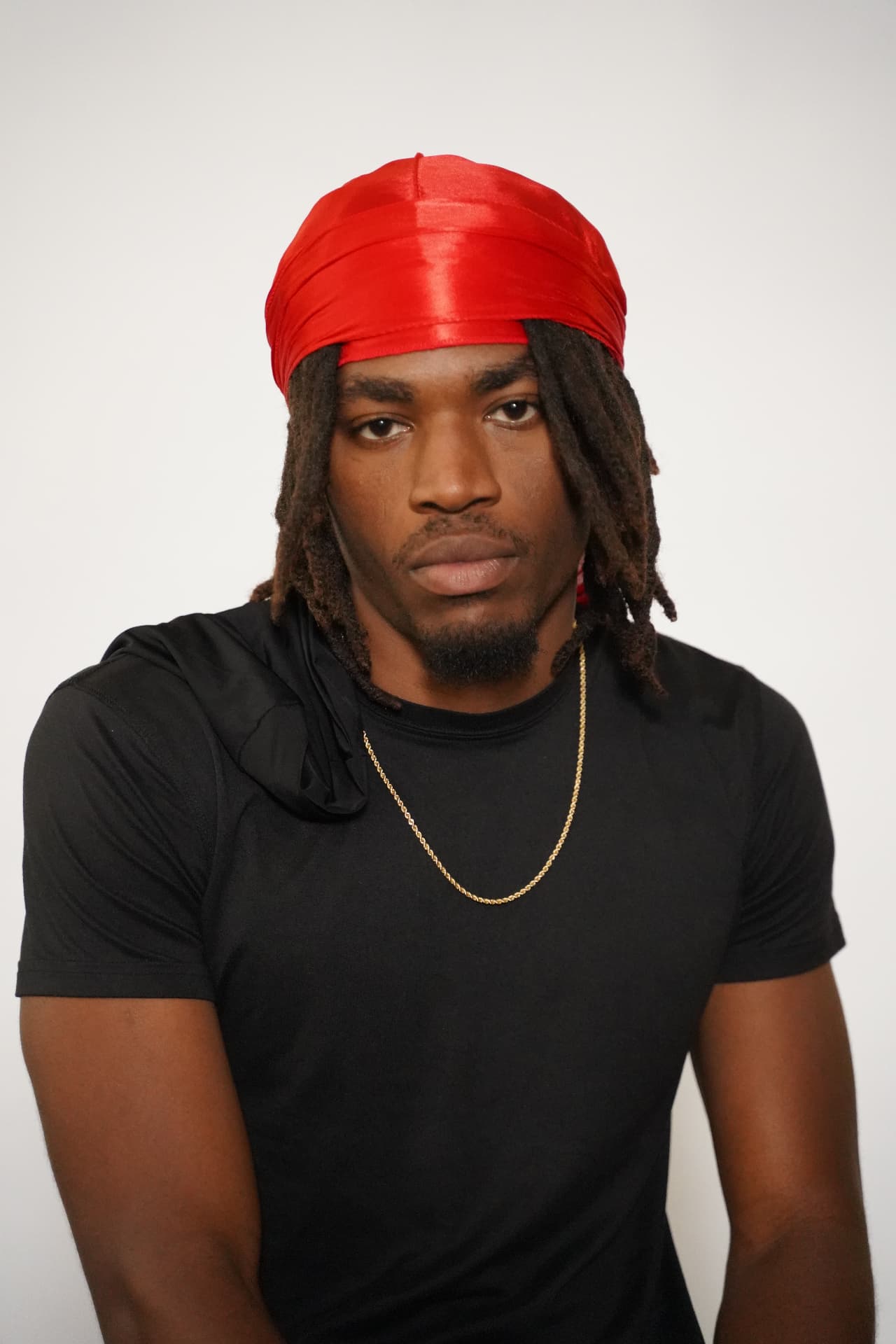 Model with locs wearing the red Elite Wrap, front view showing the wrapped band and flap