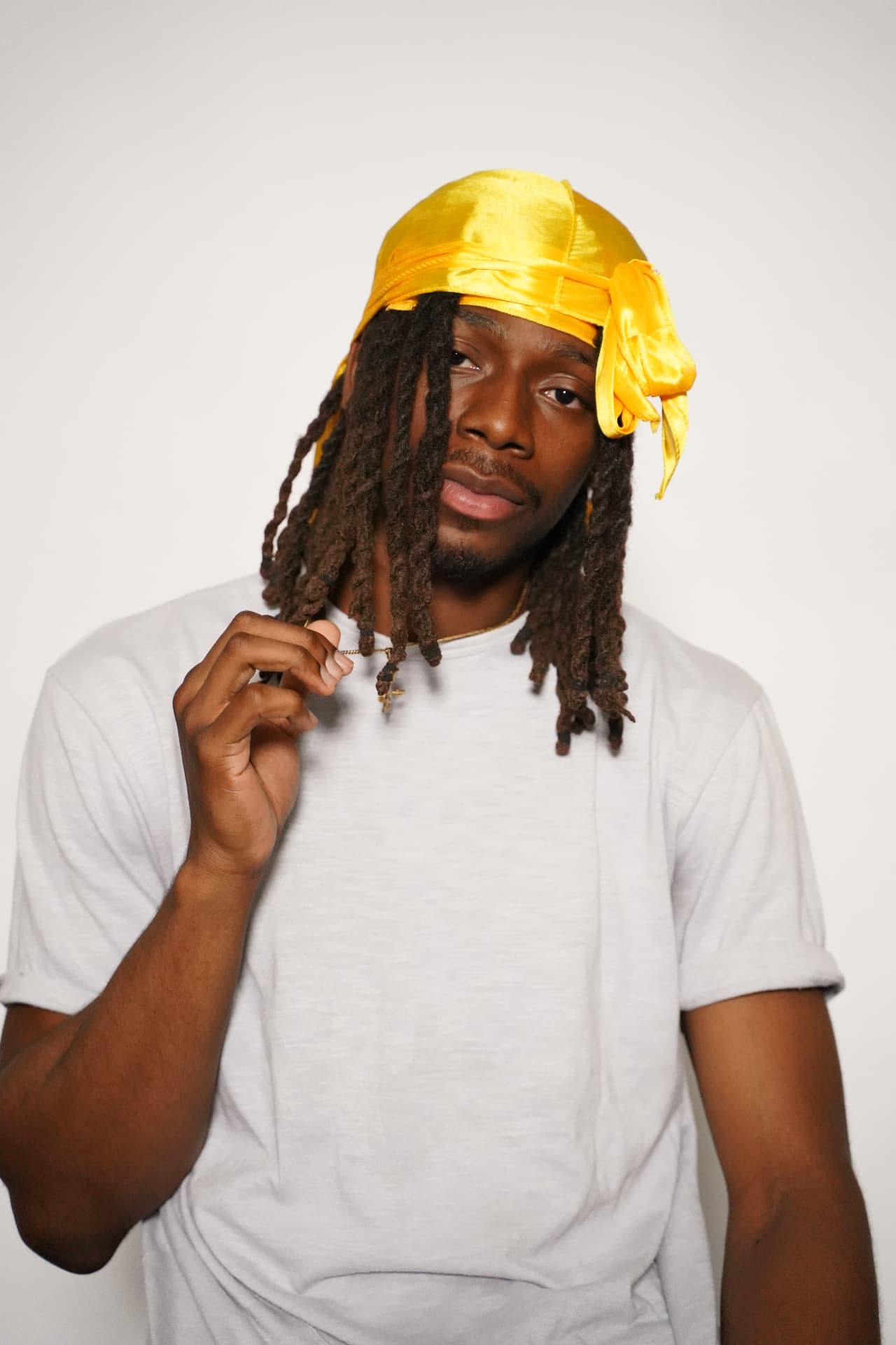 Model with locs wearing the yellow Elite Wrap, ties knotted at the side of the head